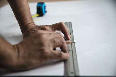 Man using measure hand tool doing wallpaper cutting work in home construction site, people with hand tool object conceptの写真素材