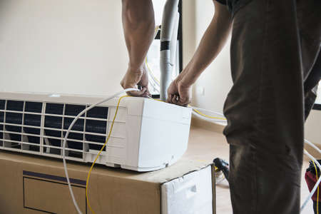 Man is installing air conditioner in housing unit during hot season in Thailand