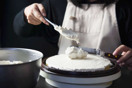 Lady making cake putting cream using spatula - homemade bakery cooking conceptの写真素材