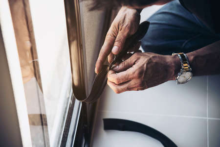 Man doing aluminum frame with glasses and wire screen door and window installation work in...