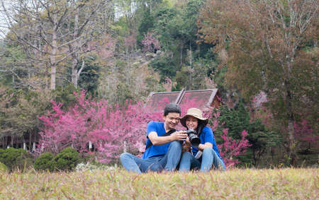 Asian couple happy taking photo in beauliful nature sakura flower garden in Doi Ang Khang, Chiangmai...