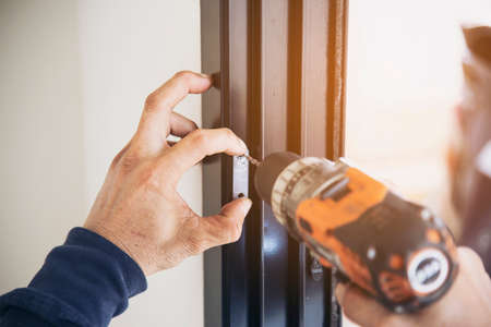 Man doing aluminum frame with glasses and wire screen door and window installation work in...