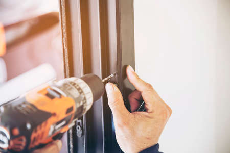 Man doing aluminum frame with glasses and wire screen door and window installation work in...