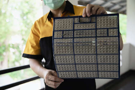 Air conditioner maintenance man showing dirty screen preparing to clean during hot season in Thailandの写真素材
