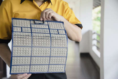 Air conditioner maintenance man showing dirty screen preparing to clean during hot season in Thailandの写真素材