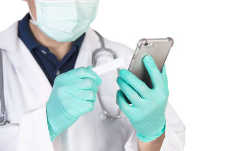 Asian doctor seriously using telephone while checking covid-19 virus antigen test kit resultの写真素材