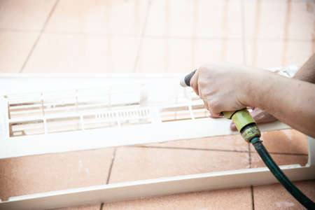 Air conditioner maintenance man cleaning a/c cover during hot season in Thailandの写真素材
