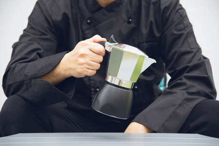 Asian barista is making hot coffee using moka pot