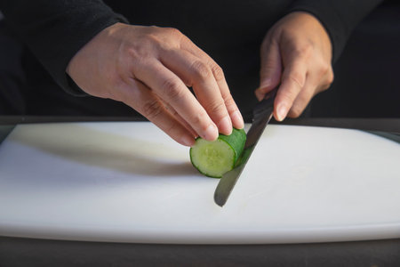 chef is preparing fresh cucumber for making japan tradition cookery menu, japanese maki sushi roll serving in oriental restaurant, various different assorted luxury mixed healthy eating set conceptの写真素材