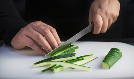 chef is preparing fresh cucumber for making japan tradition cookery menu, japanese maki sushi roll serving in oriental restaurant, various different assorted luxury mixed healthy eating set conceptの写真素材