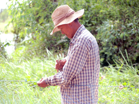RAYONG, THAILAND  - AUGUST 13 - Unidentified man mends the mesh of their fishing net on August 13,...