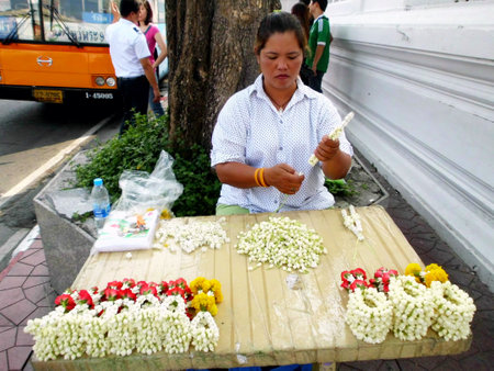 BANGKOK, THAILAND - JANUARY 4 : Unidentified woman to make flower garlands in Thai style for sell to worship at Wat Sutat on January 4, 2012 in Bangkok, Thailand.のeditorial素材