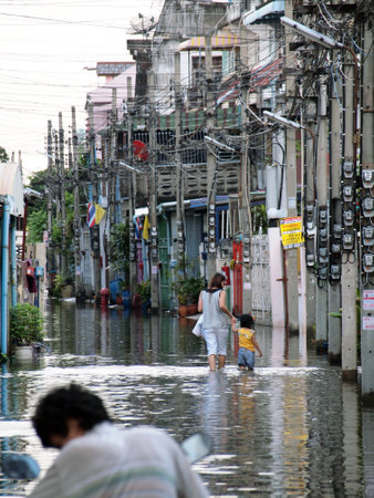 BANGKOK, THAILAND - OCTOBER 30 : Women and children walk into the home during flood on October 30,2011 Bangkok, Thailandのeditorial素材