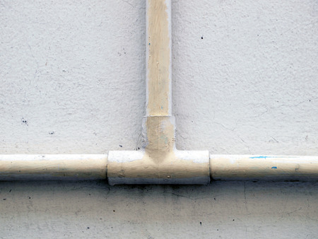 plumbing pipe against stucco wall , industrial grunge background 