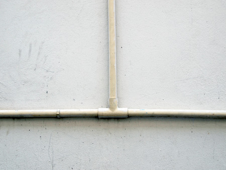 plumbing pipe against stucco wall , industrial grunge background 