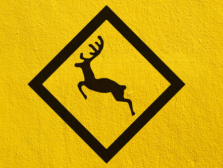 a black Deer traffic warning painted on a stucco wall outsideの写真素材