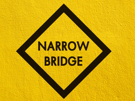 Narrow bridge Sign painted on a stucco wall outsideの写真素材