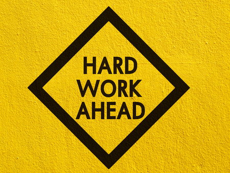 Hard work ahead street sign painted on a stucco wall outsideの写真素材