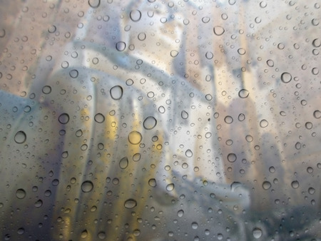 close up drops of rain on glass background. big buddha statue out of focusの写真素材