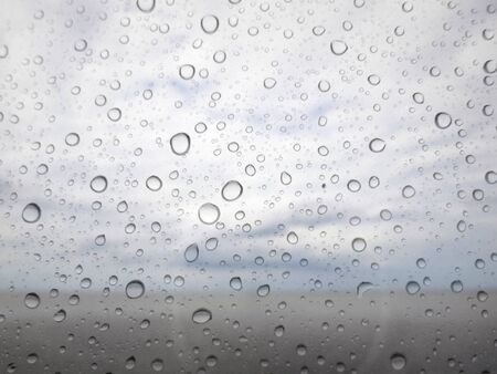 close up drops of rain on glass background. sea and sky out of focusの写真素材