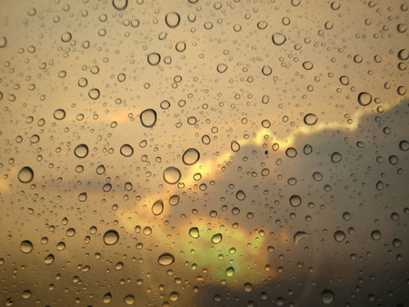 close up drops of rain on glass background. sky and cloud out of focus