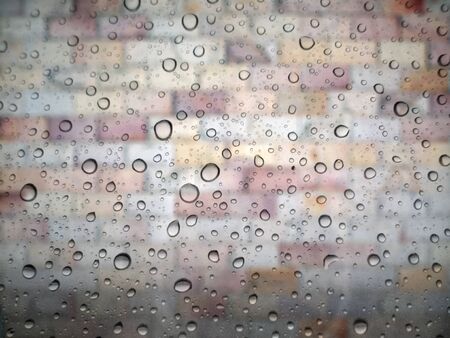 close up drops of rain on glass background. brick wall out of focusの写真素材