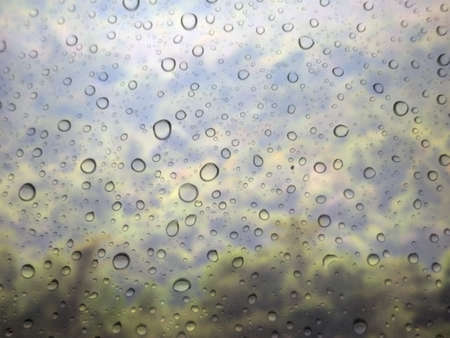 close up drops of rain on glass background. mountain out of focus
