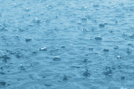 blue color tone of close up rain water drop falling to the floorの写真素材