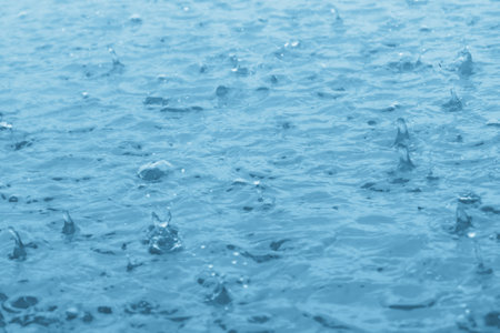 blue color tone of close up rain water drop falling to the floorの写真素材