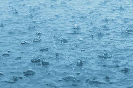 blue color tone of close up rain water drop falling to the floorの写真素材