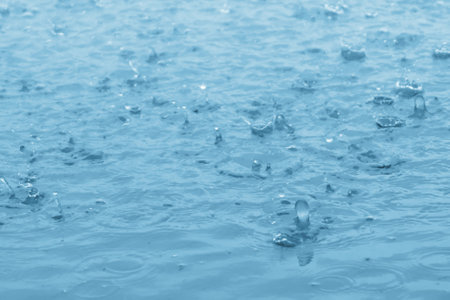 blue color tone of close up rain water drop falling to the floorの写真素材