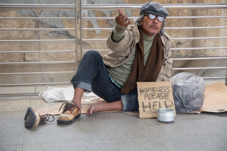 Homeless senior adult man sitting and begging in overpass