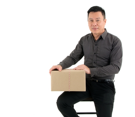 Businessman receiving a big package while posting in sitting manner on a chair isolated on white backgroundの写真素材