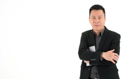 Handsome smiling business man in suit holding mobile device standing with crossed arms, isolated on white backgroundの写真素材