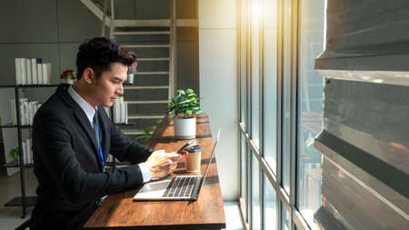 Professional Businessman By Window Working On Laptop In Coffee Shop analyzing information using...