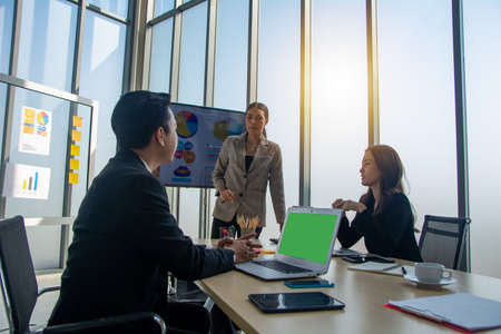 Young businesswoman coach or speaker make whiteboard presentation for diverse employees in office, focused trainer present business project on flip chart at meetingの写真素材