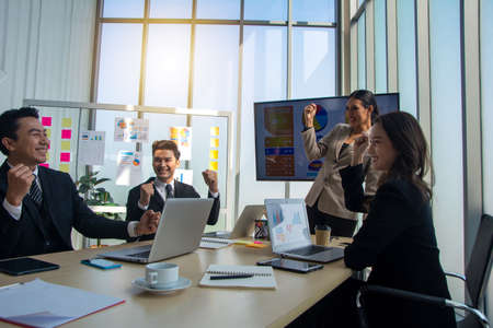 Excited business team celebrate corporate victory together in office, happy overjoyed professionals group rejoice company victory, teamwork success win triumph concept at conference table, team celebrate target achievementの写真素材