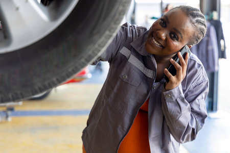 Young pregnant female customer with automotive mechanic worker, happy smiles in quality at maintenance garage, talking to her mobile phone professional vehicle service station, fix check and repair auto industry. Selective Focusの写真素材