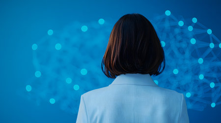 A woman in a white blazer, viewed from the back, contemplates a vibrant, connected, and abstract blue background, reflecting adaptability and innovation in a digital age.の素材