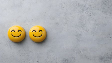 Two delightful yellow emojis with beaming smiles stand out on a subtly textured gray backdrop, evoking joy and playfulness. The atmosphere feels cheerful and light.の素材