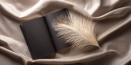 An elegant open book paired with a fluffy feather on a soft beige silk background creates an inspiring and artistic composition perfect for creative projects.の素材
