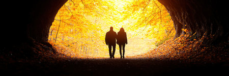 A heartwarming scene of a couple walking together under a canopy of golden autumn leaves, creating a romantic atmosphere filled with tranquility.の素材