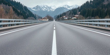 A peaceful road leads towards the majestic mountains, framed by lush greenery and a cloudy sky, perfect for adventure and travel themes.の素材