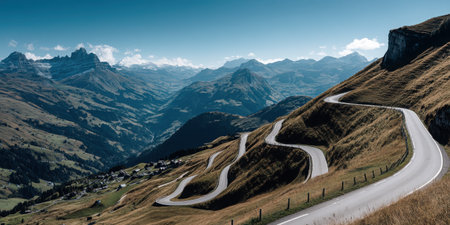 A stunning view of a winding mountain road meandering through an expansive alpine landscape under a bright blue sky. Ideal for travel enthusiasts.の素材