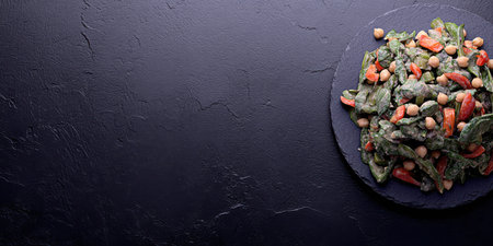 A delicious, fresh spinach salad topped with chickpeas and cherry tomatoes, drizzled with creamy dressing. Perfect for healthy eating.の素材