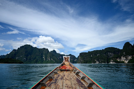 Explore the breathtaking beauty of nature with this image showcasing a traditional longtail boat. Surrounded by majestic mountains and clear waters, this scene captures the essence of adventure and tranquility.の素材