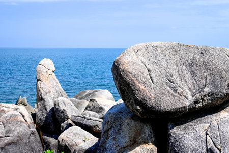 Scenic rocky shoreline with clear blue ocean under a bright sky, creating a tranquil atmosphere...