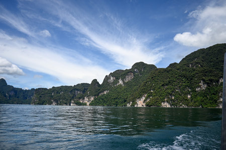 A breathtaking view capturing lush green mountains rising sharply from clear blue waters, ideal for...