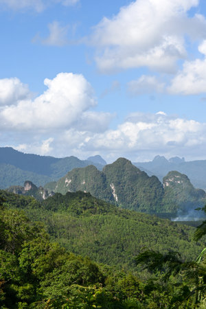 This stunning image captures a vibrant landscape of lush green mountains beneath a bright blue sky...