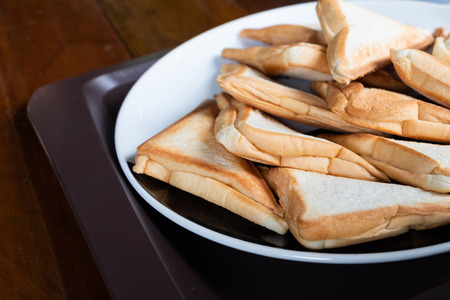 Breakfast Toast Sandwich on white plate in brown plastic tray on wood table